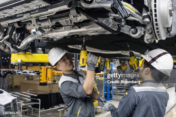 Workers connect the drive train and the body frame of a Vinfast Lux SA2.0 sports utility vehicle moving along a conveyor at the automaker's factory...