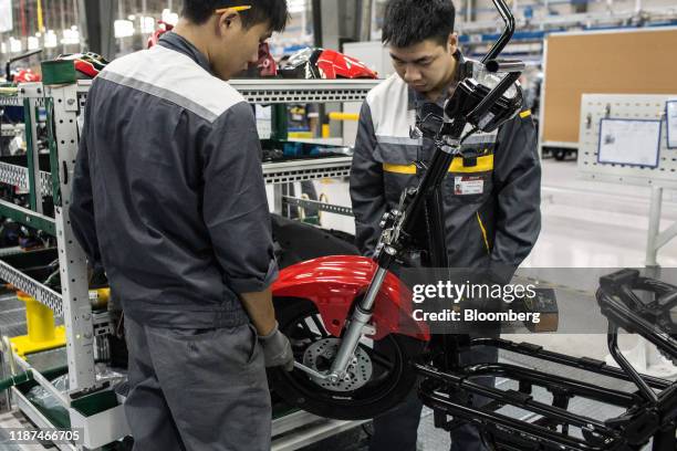 Engineers use a torque gun to tighten the wheel bolt on a Vinfast Impes electric scooter on the assembly line at the automaker's factory in Haiphong,...
