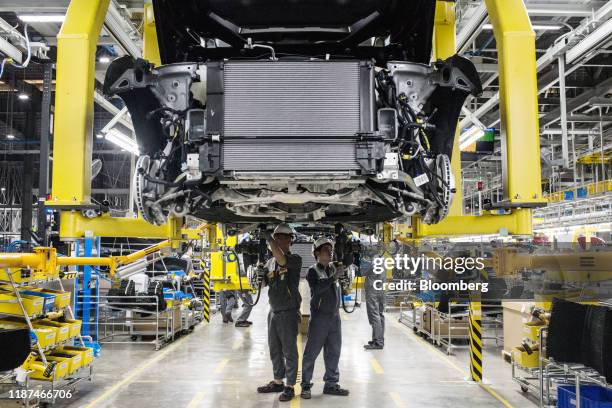 Workers connect the drive train and the body frame of a Vinfast Lux SA2.0 sports utility vehicle moving along a conveyor at the automaker's factory...