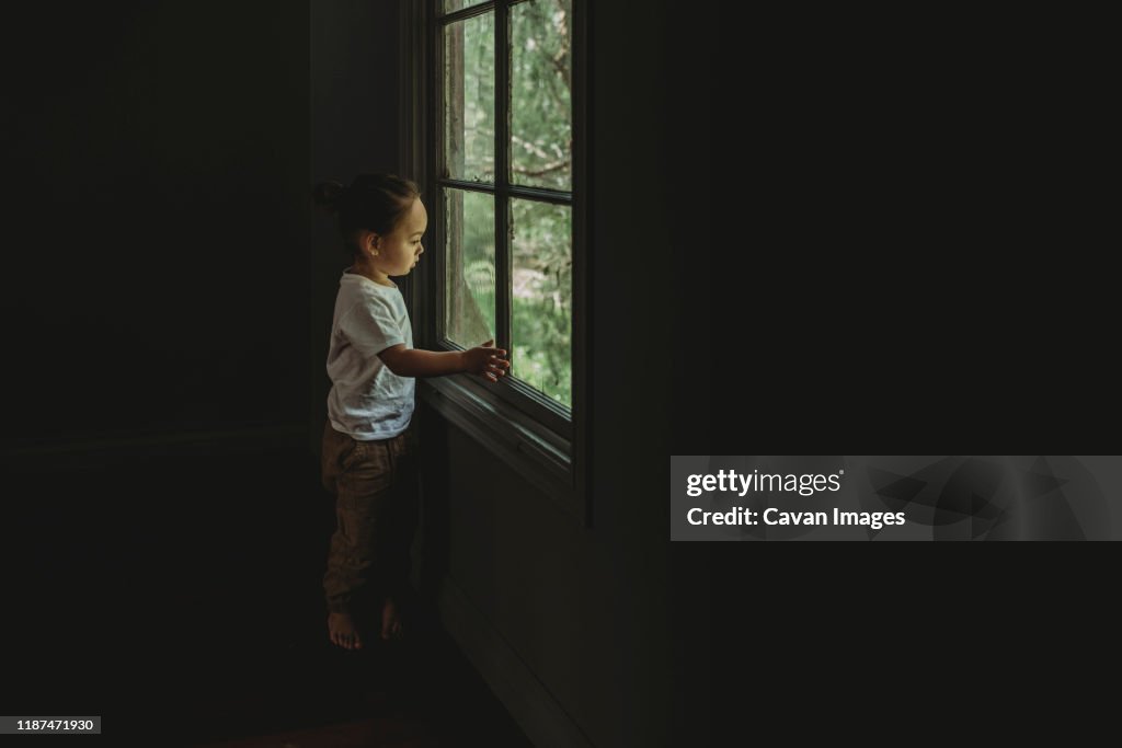 Preschool aged boy looking out the window at the trees