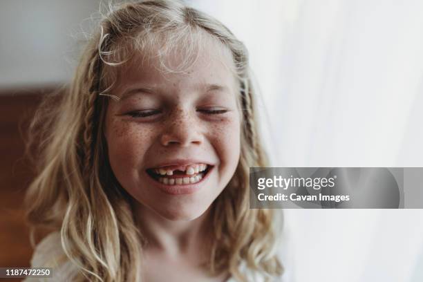 portrait of young freckled smiling girl missing tooth with eyes closed - freckle girl stock pictures, royalty-free photos & images