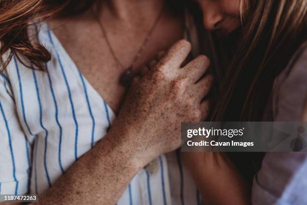 close up of freckled mother's hand embracing daughters - freckle arm stock pictures, royalty-free photos & images