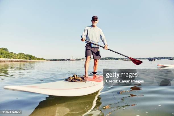 Mature male standup paddle boarder has fun in Casco Bay, Maine