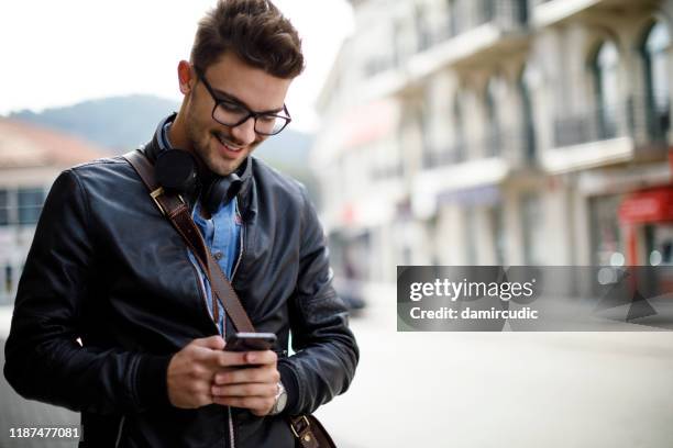 lachende jonge man met behulp van mobiele telefoon buiten - male student wearing glasses with friends stockfoto's en -beelden