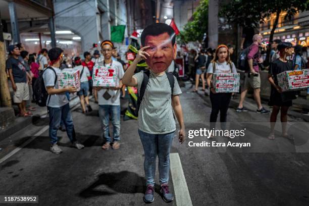 Woman holds up a picture of Philippine President Rodrigo Duterte as she takes part in a protest marking International Human Rights Day on December...