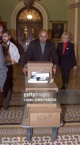 Capitol staff member Rogers Ferguson wheels some of the boxes containing evidence and testimony from the House Judiciary Committee's impeachment case...