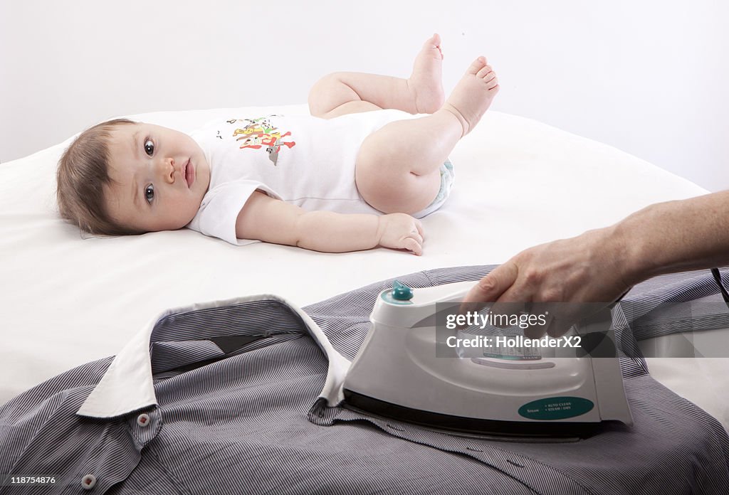 Baby on ironing board while parent is ironing
