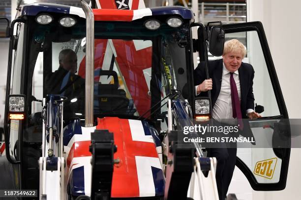 Britain's Prime Minister and Conservative party leader Boris Johnson exits the cab of a Union flag-themed JCB, after driving through a fake wall...