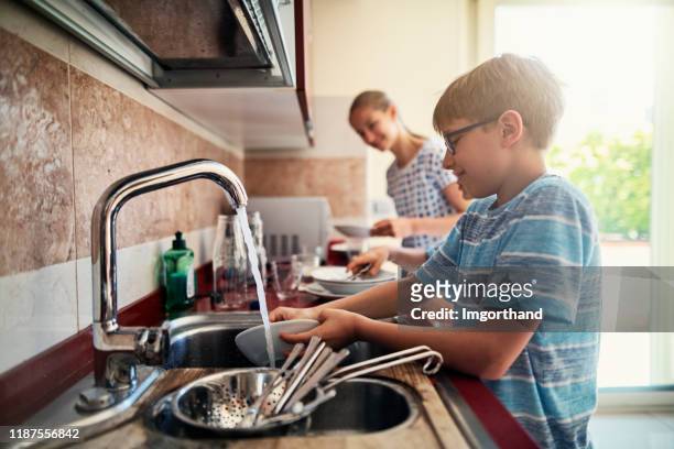 gosses lassant la vaisselle après le déjeuner - domestic chores photos et images de collection