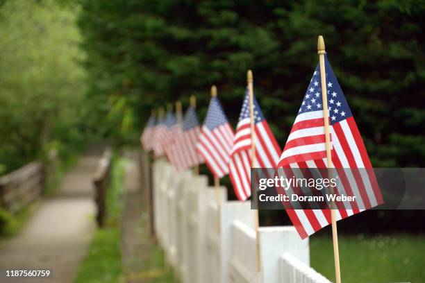 medium size american flags line white fence - fourth of july decorations stock pictures, royalty-free photos & images