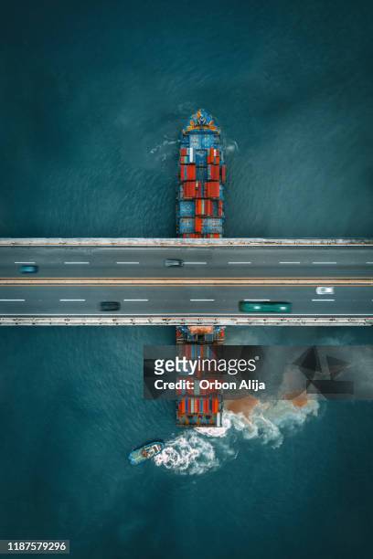 barco de carga contenedor que navega bajo un puente de carretera - punto de vista de dron fotografías e imágenes de stock