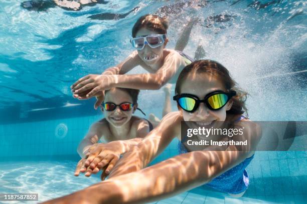 glückliche kinder schwimmen unter wasser im pool - schwimmen schwimmbad stock-fotos und bilder