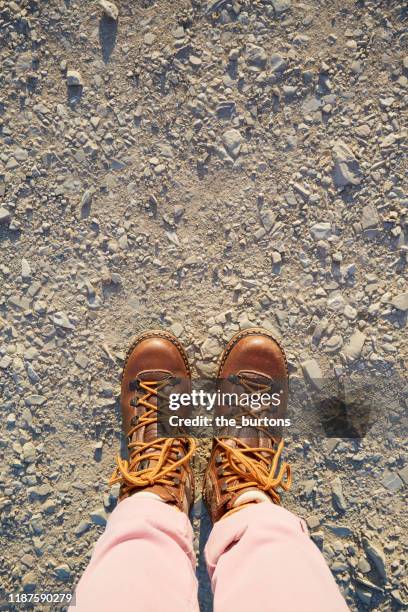 woman in hiking boots standing on rock, stones and gravel surface - hiking boot stock pictures, royalty-free photos & images