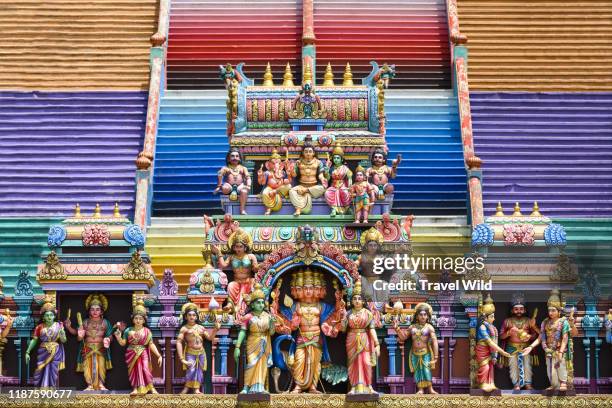 (Selective focus) Representation of Hindu gods and tourists climbing a colorful stairs leading to the Batu Caves in the background. Kuala Lumpur, Malaysia