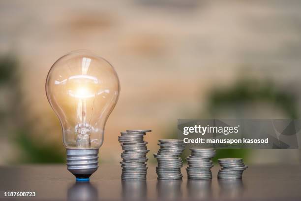 coins and light bulb. concept saving money. - saving electricity stock pictures, royalty-free photos & images