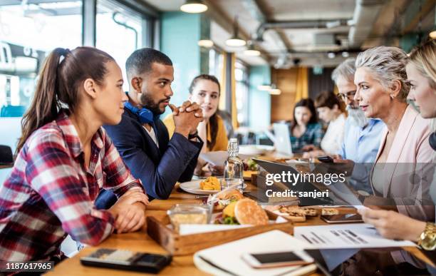 geschäftsleute diskutieren beim mittagessen in einer cafeteria - breakfast meeting stock-fotos und bilder