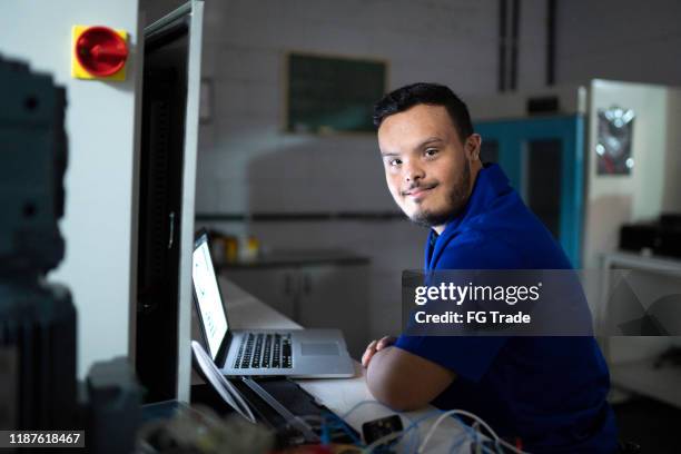 porträt von sonderbedürfnissen mitarbeiter mit laptop in der industrie - diversity people industry stock-fotos und bilder