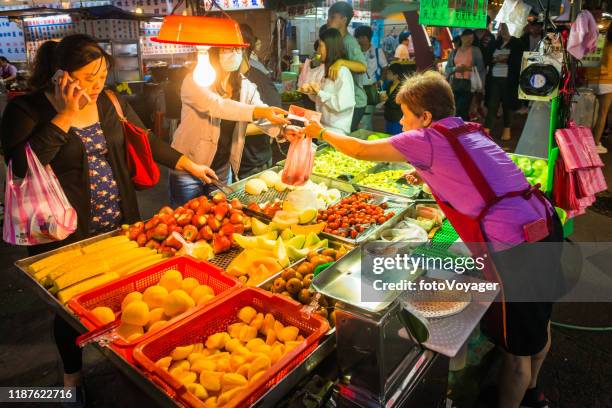 taipei women at fruit grocery stall in night market taiwan - taiwan night market stock pictures, royalty-free photos & images