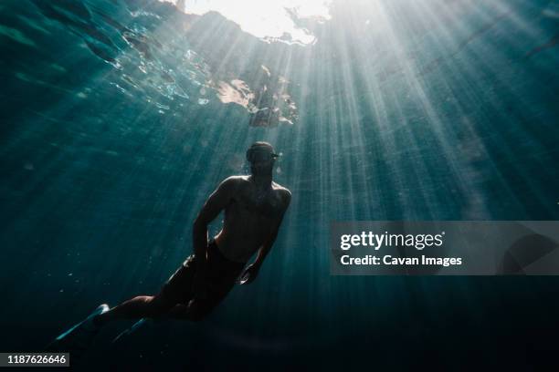 full length of a man swimming underwater in the ocean - free diving stockfoto's en -beelden