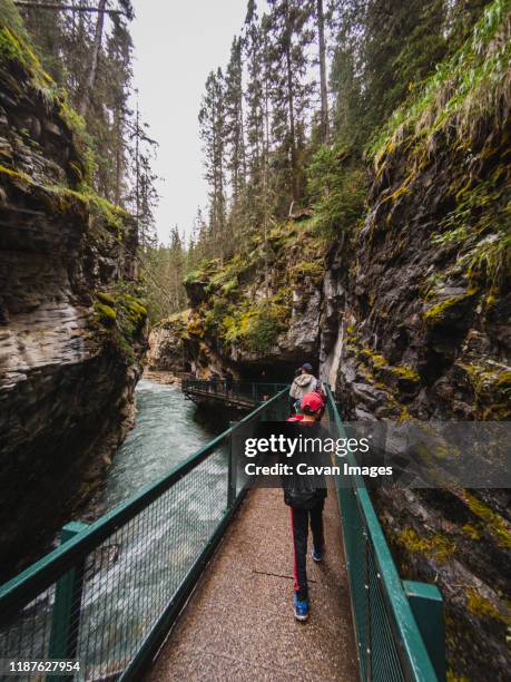 people walking on metal catwalk alongside the flowing water in canyon. - kids catwalk stock pictures, royalty-free photos & images