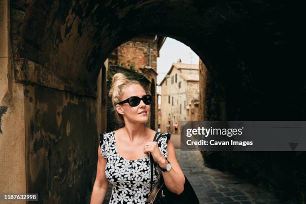 woman in black glasses walking out of dark tunnel into light - montalcino imagens e fotografias de stock