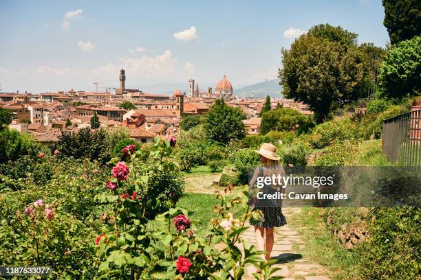 woman walking in blooming garden in aged city - florencia fotografías e imágenes de stock