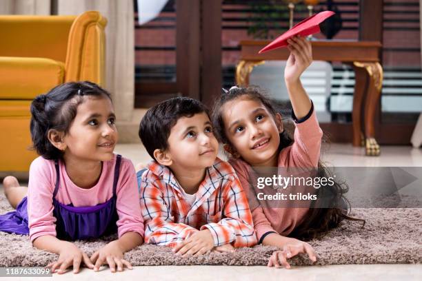 bambini che giocano con l'aereo di carta a casa - giorno dei bambini foto e immagini stock