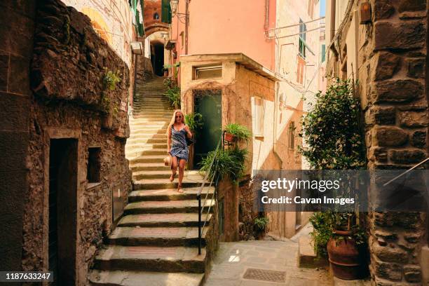 woman walking downstairs in ancient european street - narrow foto e immagini stock