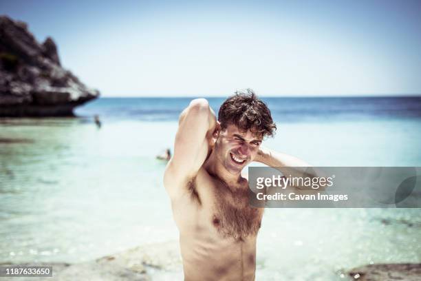 handsome man stretches and smiles on beautiful blue beach in australia - rottnest island stock pictures, royalty-free photos & images