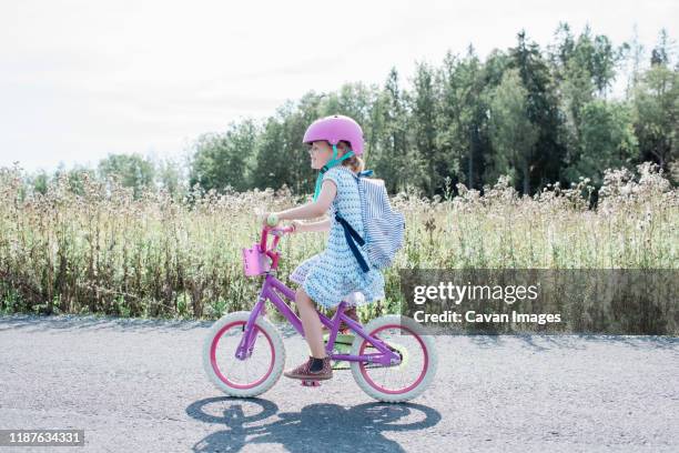 young girl cycling along a country lane smiling in summer - training wheels stock pictures, royalty-free photos & images