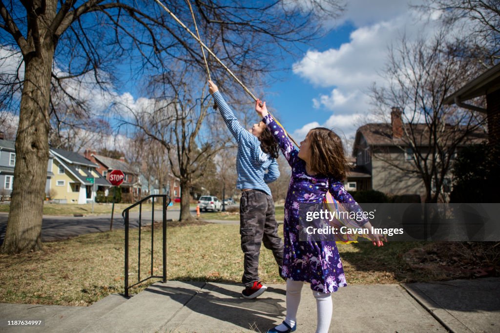 Child Stooping Two Happy Children Play With Sticks On Their Front Stoop High-Res Stock ...