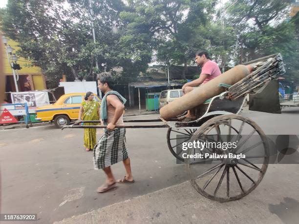 Poor labourer pulls a hand pulled rickshaw or a cart on the roads of Kolktta on November 6, 2019 in Kolkatta, India. The air pollution was very...