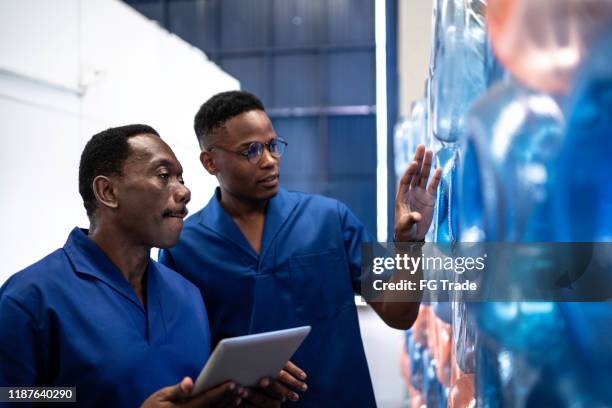 colleagues (father and son) using digital tablet and working in industry - gallon stock pictures, royalty-free photos & images