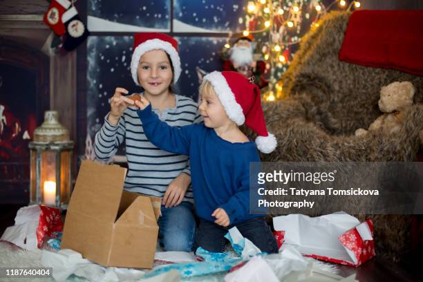 beautiful children, toddler and school boy, opening presents on christmas night, secretly sneaking in the room - tiny beautiful things opening night celebration stock pictures, royalty-free photos & images