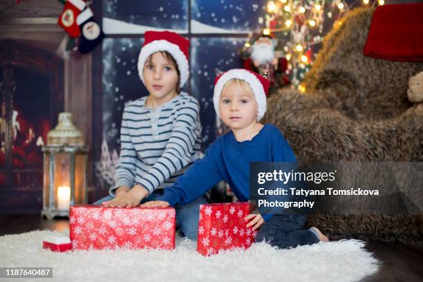 beautiful children, toddler and school boy, opening presents on christmas night, secretly sneaking in the room - tiny beautiful things opening night celebration stock pictures, royalty-free photos & images