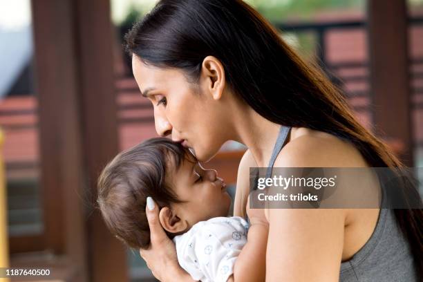 mother holding sleeping baby boy - indian baby boy stock pictures, royalty-free photos & images