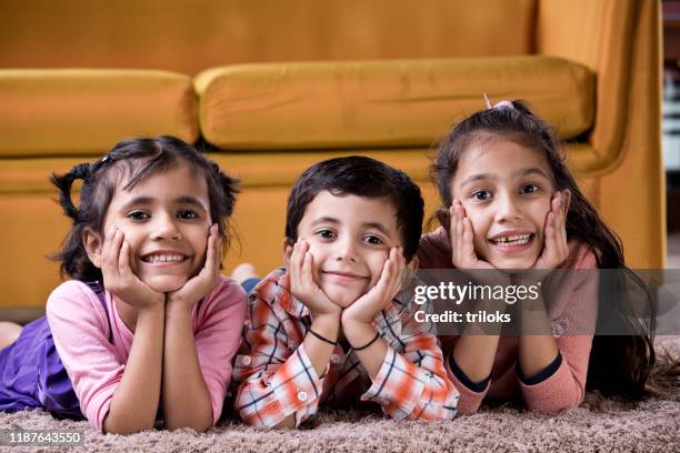 bambini appoggiati sul tappeto a casa - giorno dei bambini foto e immagini stock