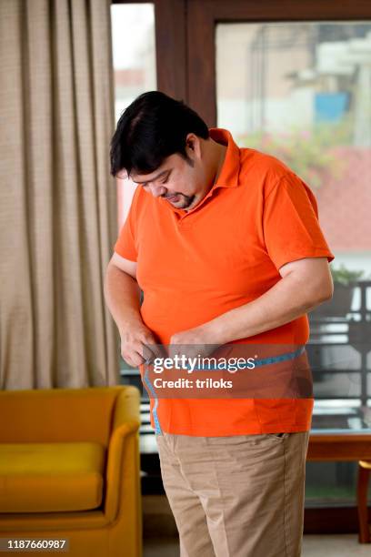 obese man measuring his belly - fat guy belly stock pictures, royalty-free photos & images
