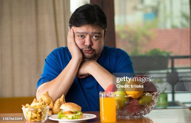 displeased man with unhealthy and healthy food on table - healthy fats stock pictures, royalty-free photos & images