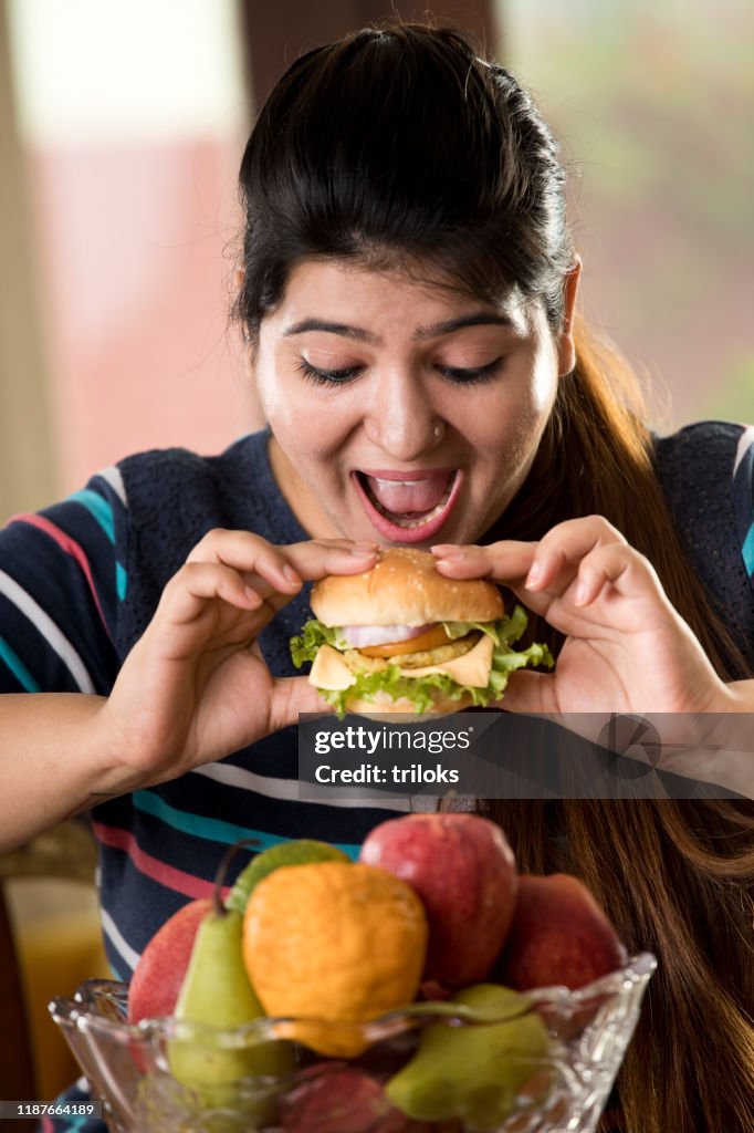 Donna che mangia un hamburger fast food