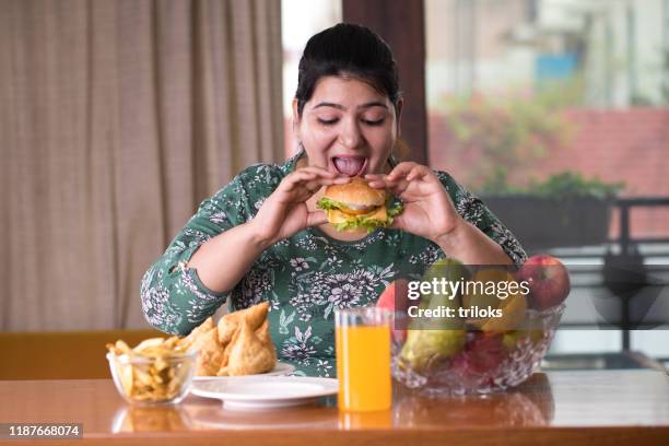 donna che mangia un hamburger fast food - fat foto e immagini stock