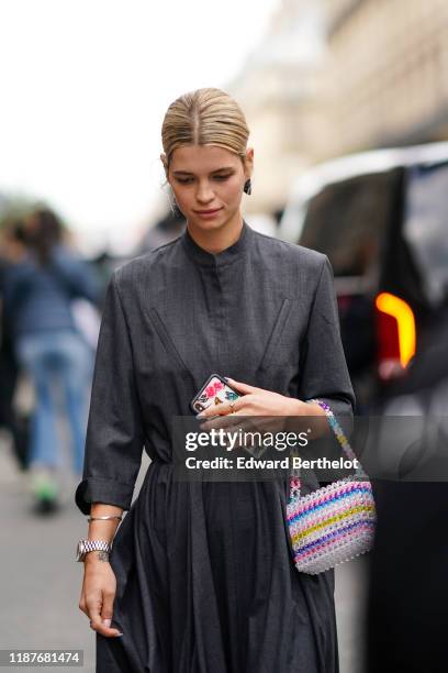 Pixie Geldof wears a gray dress, earrings, a multicolor beaded bag, bracelets, a ring, outside Giambattista Valli, during Paris Fashion Week -...