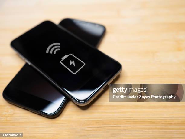 two smart phones sharing charge on a wooden table - 4g stock pictures, royalty-free photos & images