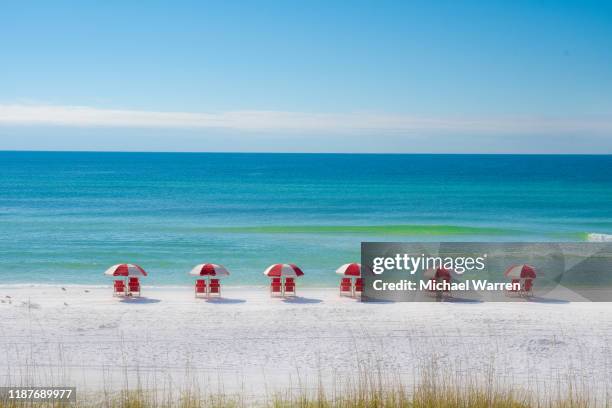 bunte reihe von roten stühlen am strand - golfküstenstaaten stock-fotos und bilder