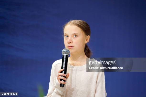 December 2019, Spain, Madrid: Greta Thunberg, Swedish climate activist, speaks at an event at the UN Climate Change Conference, holding a microphone...