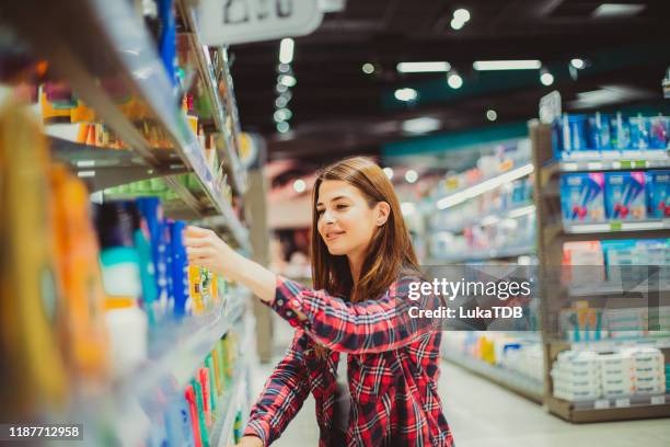 a girl choosing a lotion in the supermarket - convenience storefront stock pictures, royalty-free photos & images