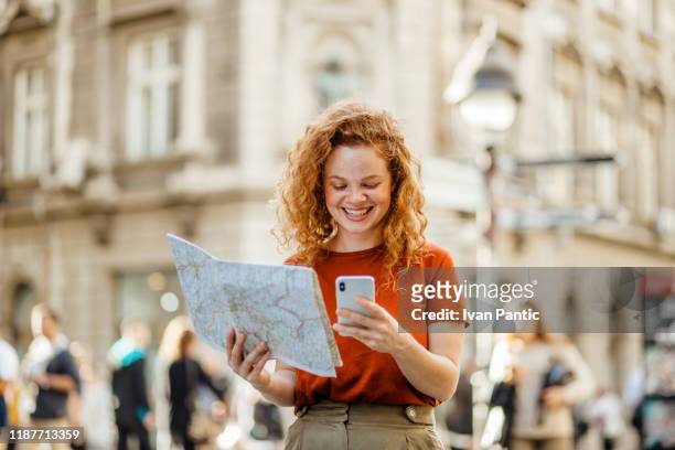 pretty young woman with curly hair trying to get her bearings - travel guidance stock pictures, royalty-free photos & images