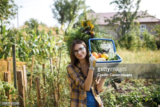 the farmer girl holding basket full of vegetables on green farm - homegrown produce stock photos et images de collection