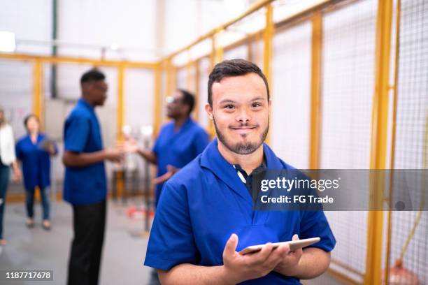 retrato de empleados con necesidades especiales que sostienen tabletas digitales en la industria - down's syndrome fotografías e imágenes de stock