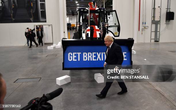 Britain's Prime Minister and Conservative party leader Boris Johnson walks past a Union flag-themed JCB, after driving it through a fake wall...